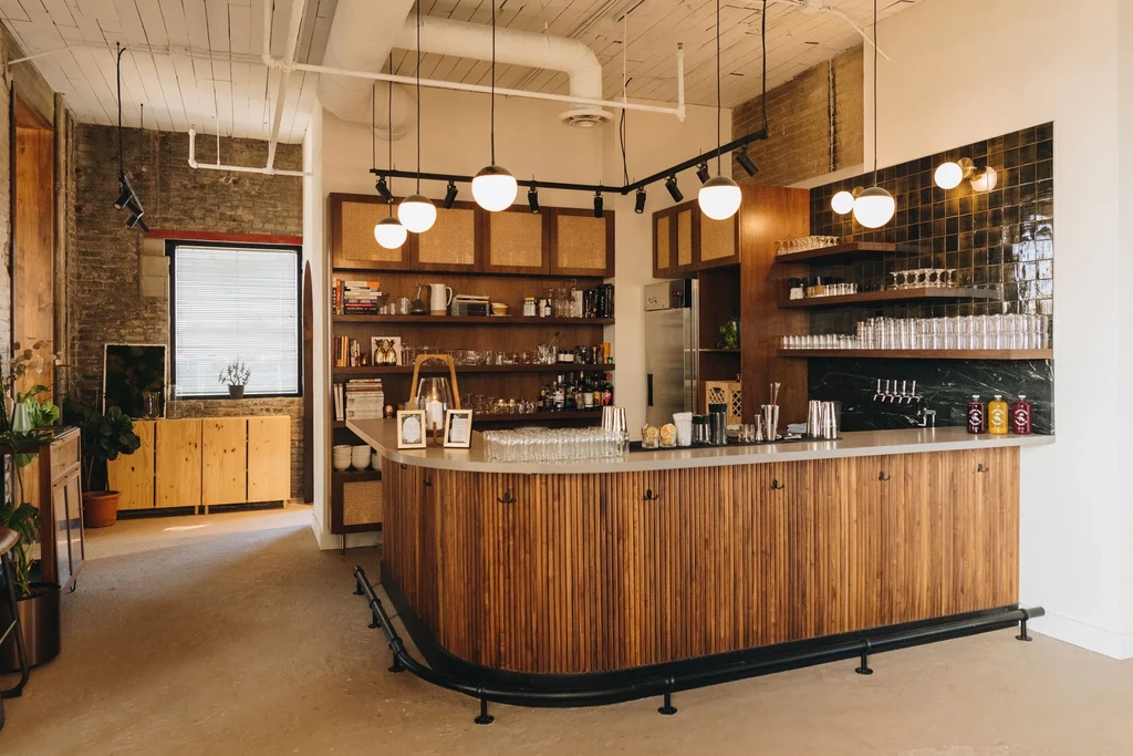 Modern, rustic-industrial bar interior with a large curved wooden counter.