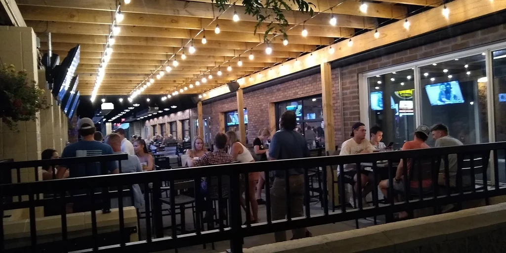 Lively evening restaurant patio with string lights and many people.