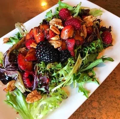 Green salad with strawberries, raspberries, blackberries, and pecans.