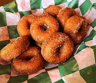 Golden-brown sugar-coated doughnuts and donut holes in a checkered basket.