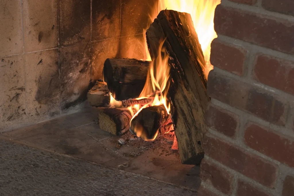 Roaring fire with burning logs in a sooty stone fireplace.