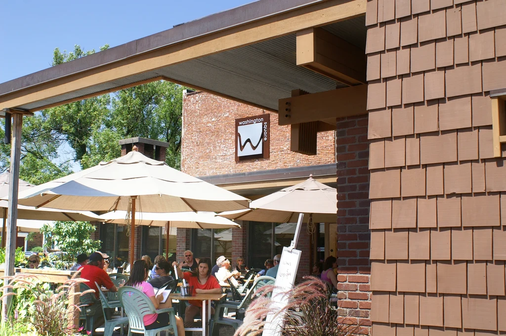 Lively outdoor restaurant patio with many people dining under umbrellas.