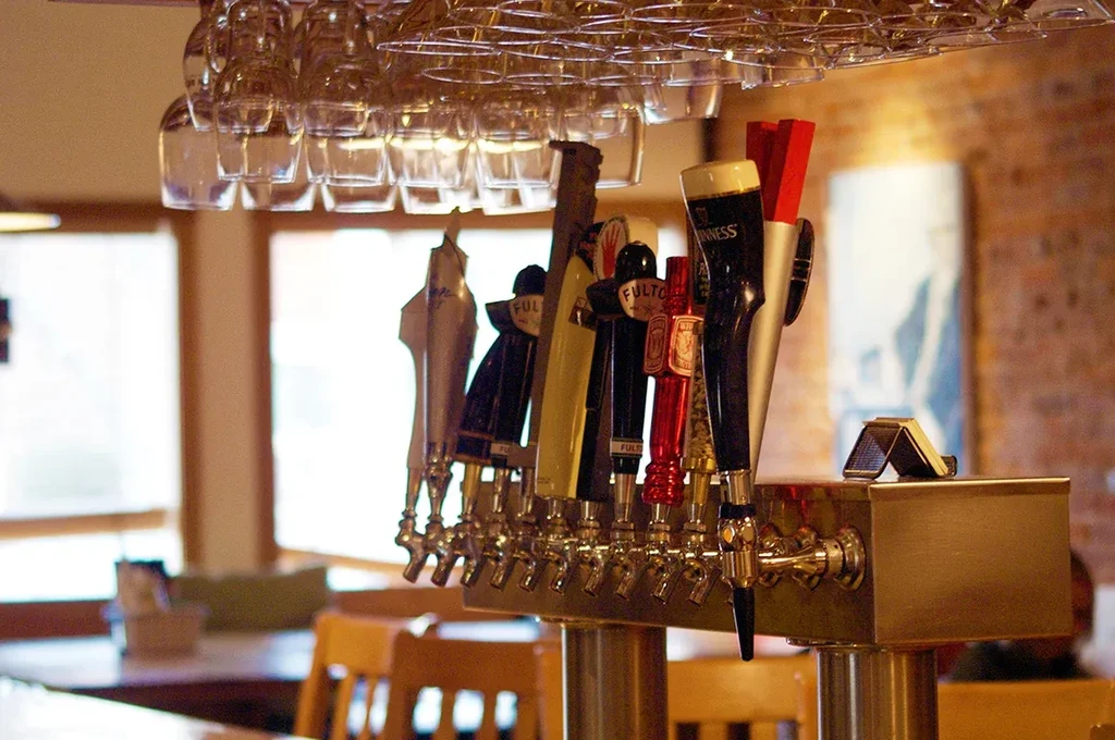 Bright bar interior with beer taps, Guinness handle, and inverted glasses.