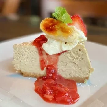 Creamy cheesecake slice with strawberry compote, whipped cream, mint, banana.