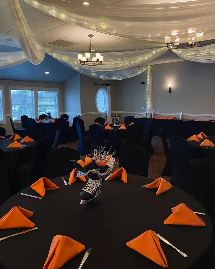 Warmly lit event space with draped ceiling, black tables, ice skate decor.