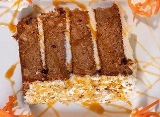 Overhead layered carrot cake slice with white frosting and caramel drizzle.