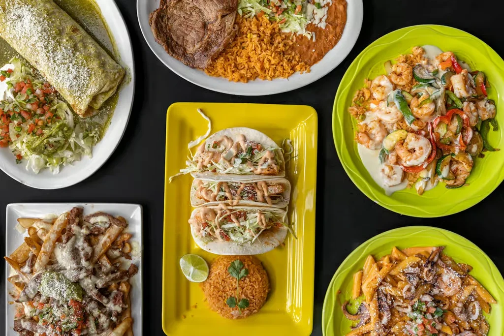 Overhead view of a diverse spread of colorful Mexican-style dishes.