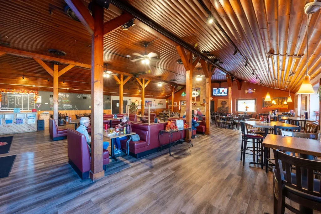 Spacious, rustic restaurant with extensive wood, red booths, and patrons.