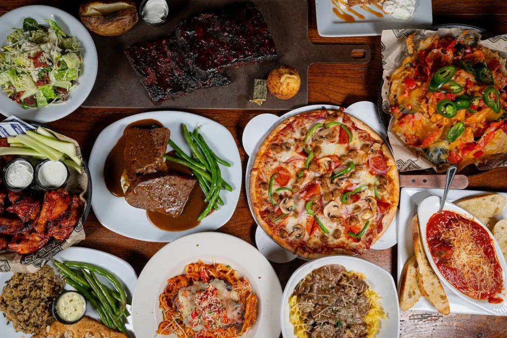 A diverse spread of prepared dishes laid out on a dark wooden table.
