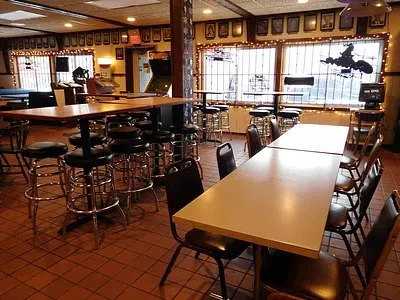 Dimly lit casual restaurant with high-top and dining tables, plus arcade machines.