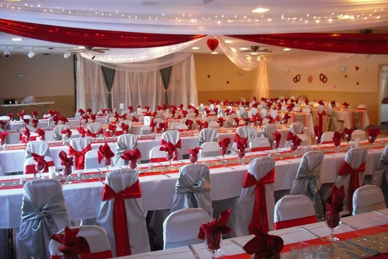 Red and white banquet hall with draped ceiling, string lights, and red heart.