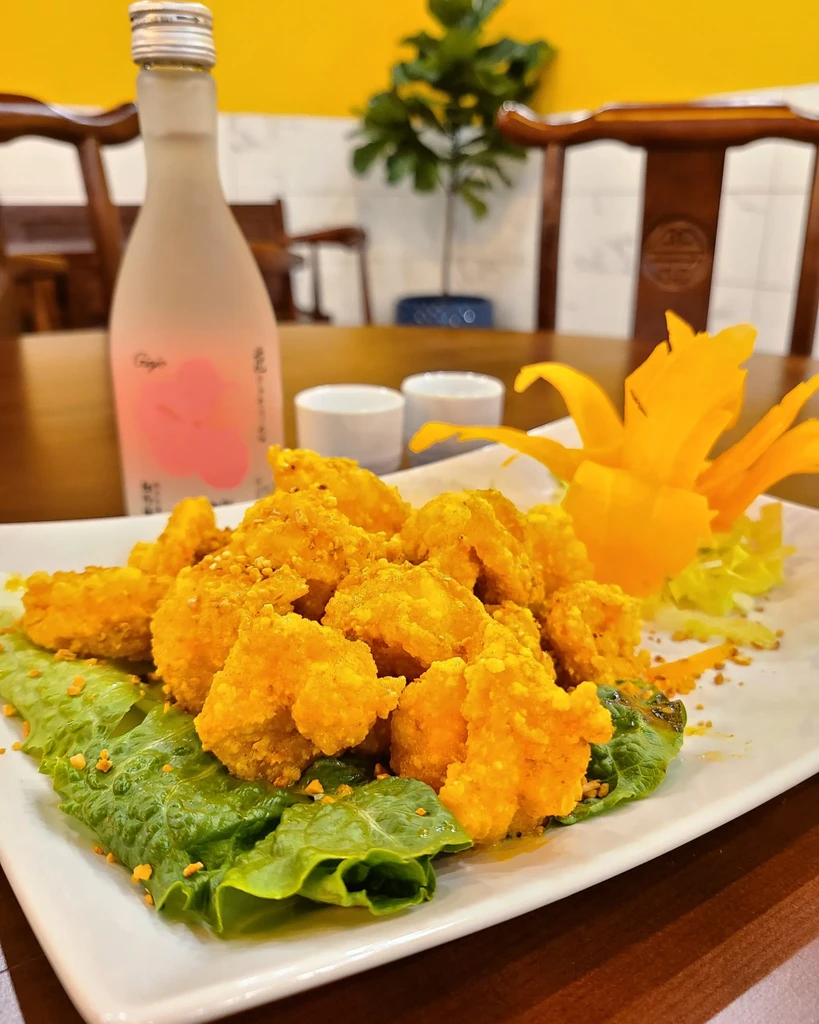 Golden-brown fried food on lettuce with orange garnish on a white plate.