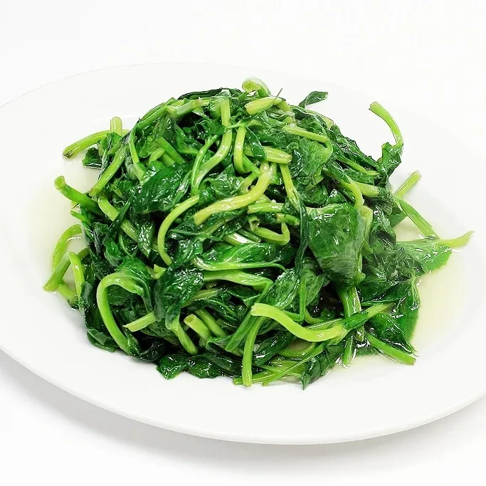Vibrant cooked green leafy vegetables on a plain white plate.