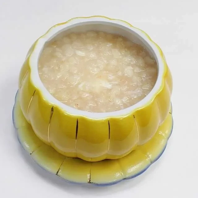 Top-down: light porridge in yellow scalloped bowl and matching saucer.