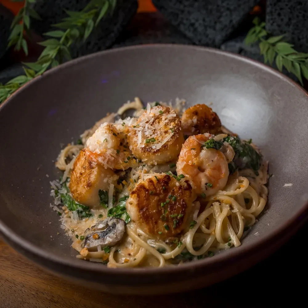 Creamy pasta with seared scallops, shrimp, vegetables, and mushrooms.