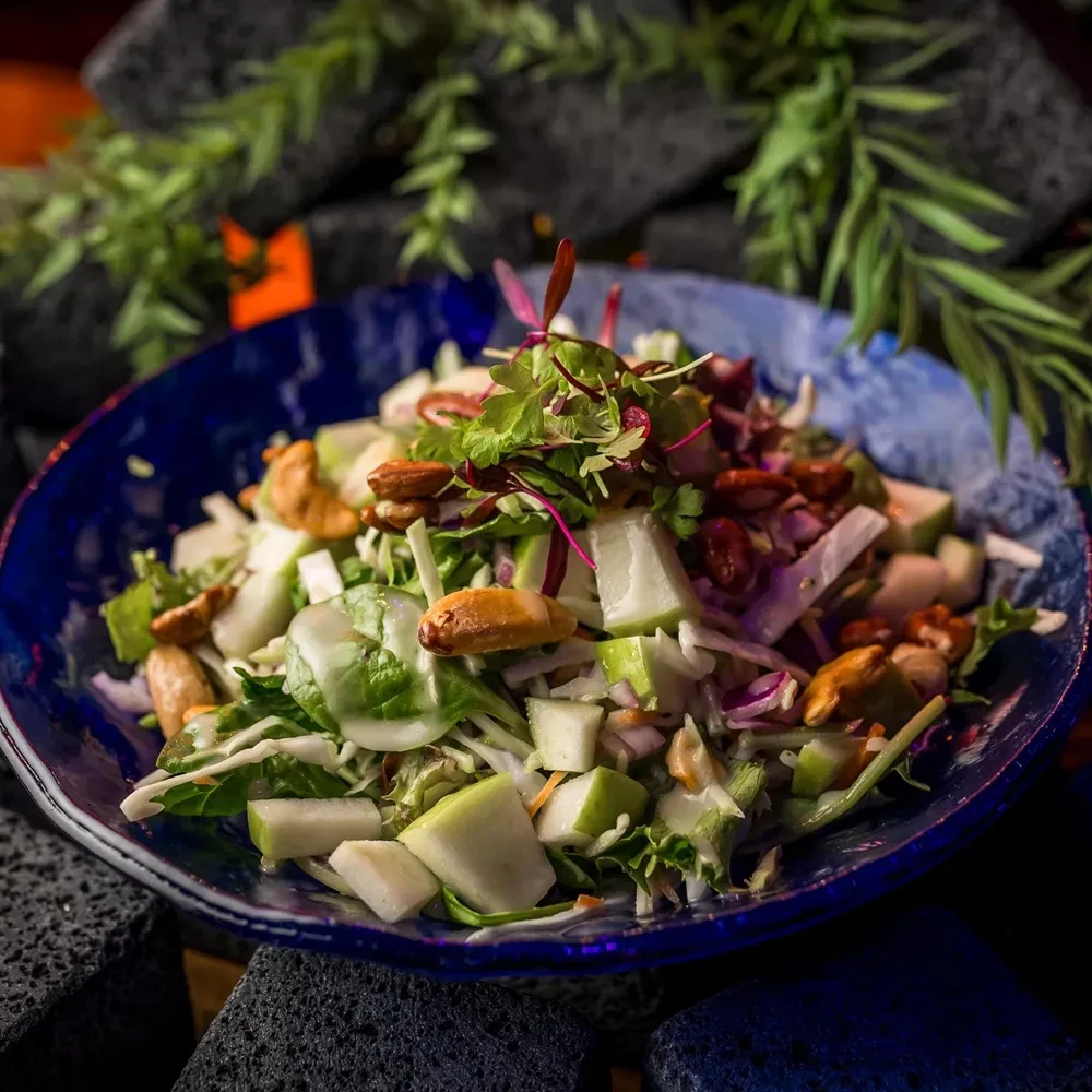 Fresh salad with greens, cabbage, fruit, nuts, and creamy dressing.
