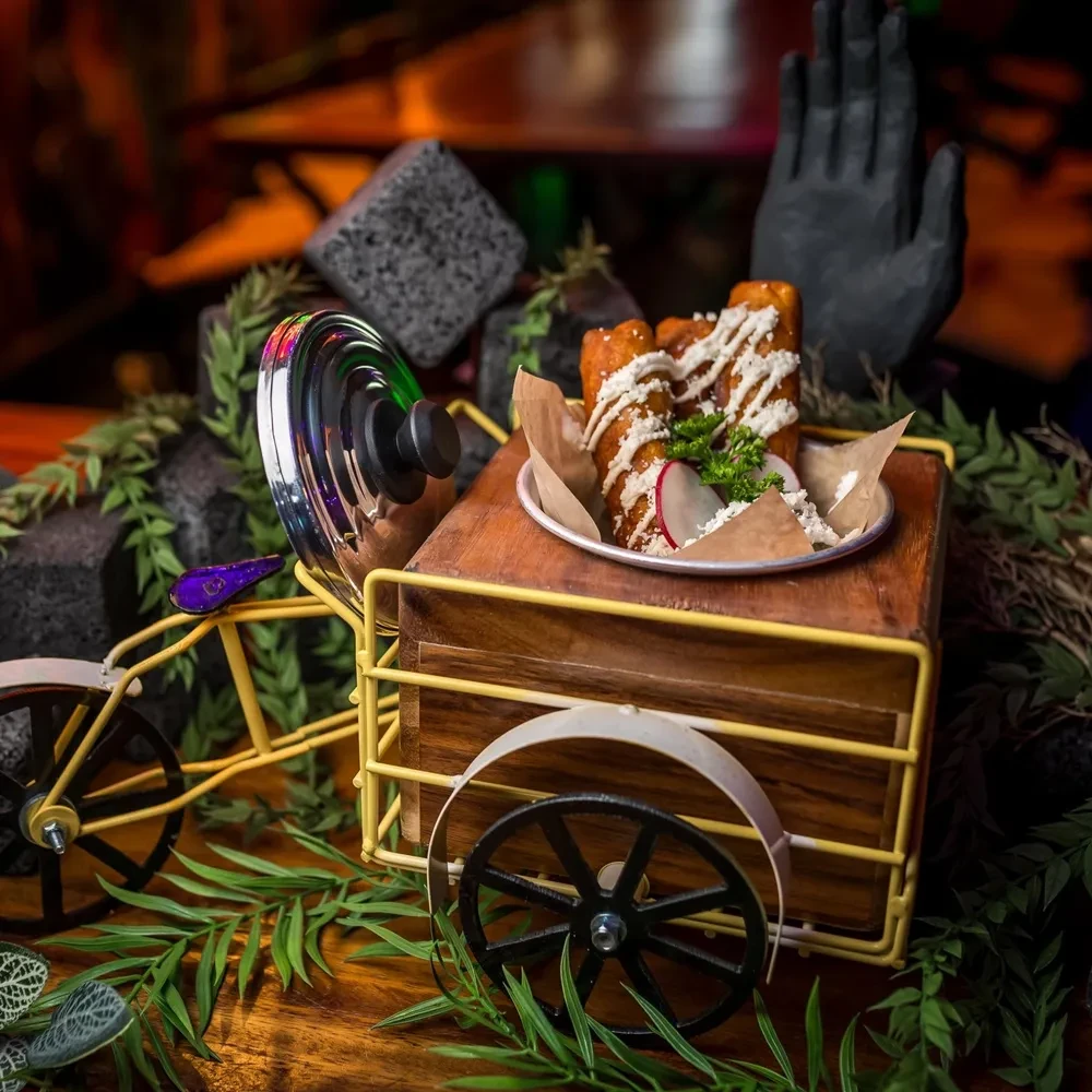 Fried rolls with creamy sauce and cheese on a decorative yellow mini-cart.