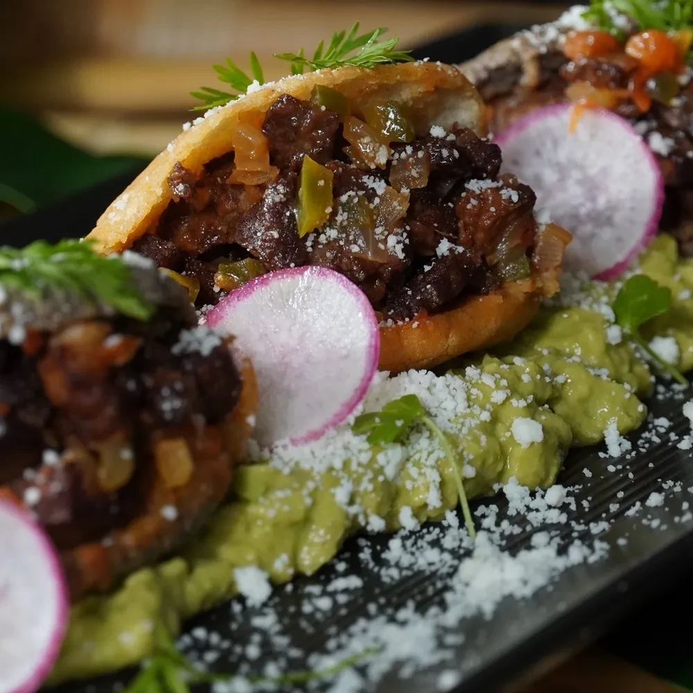 Stuffed masa pockets with meat, radish, cheese, herbs, and guacamole.