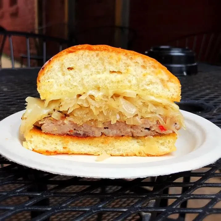 Cross-section sandwich with patty, caramelized onions, and cheese on a plate.