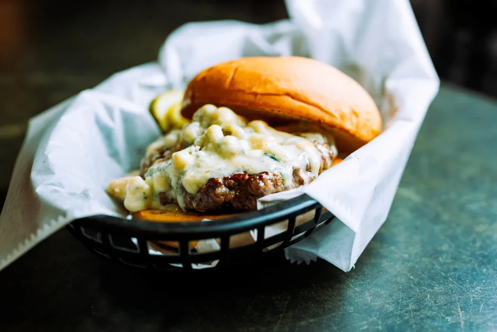 Gourmet beef burger with creamy white sauce, brioche bun, and pickles.