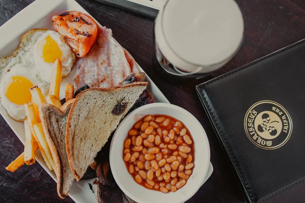 Full Irish breakfast with eggs, bacon, fries, beans, and pub menu.