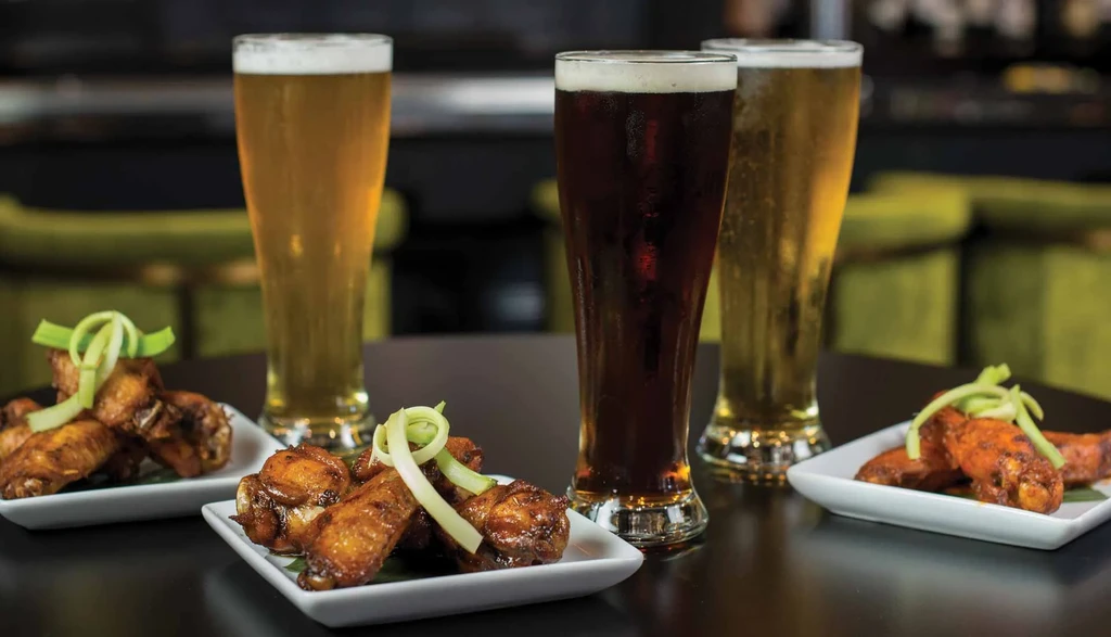 Two lagers, a stout, and three plates of glazed chicken wings.