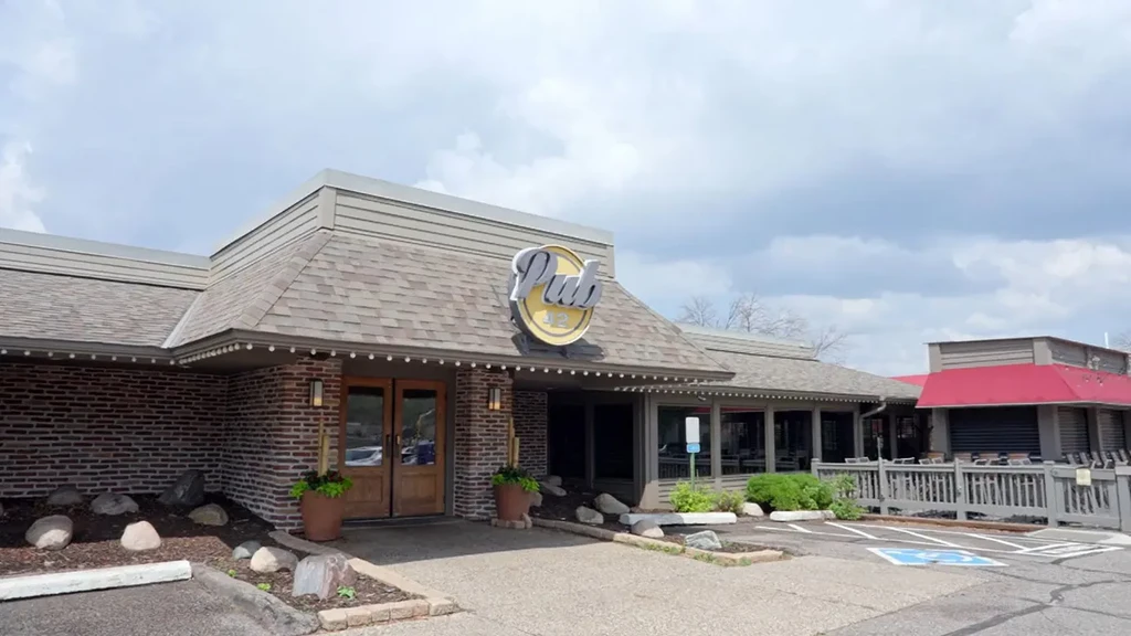Front facade of Pub 42 with sign, patio, and handicap parking.