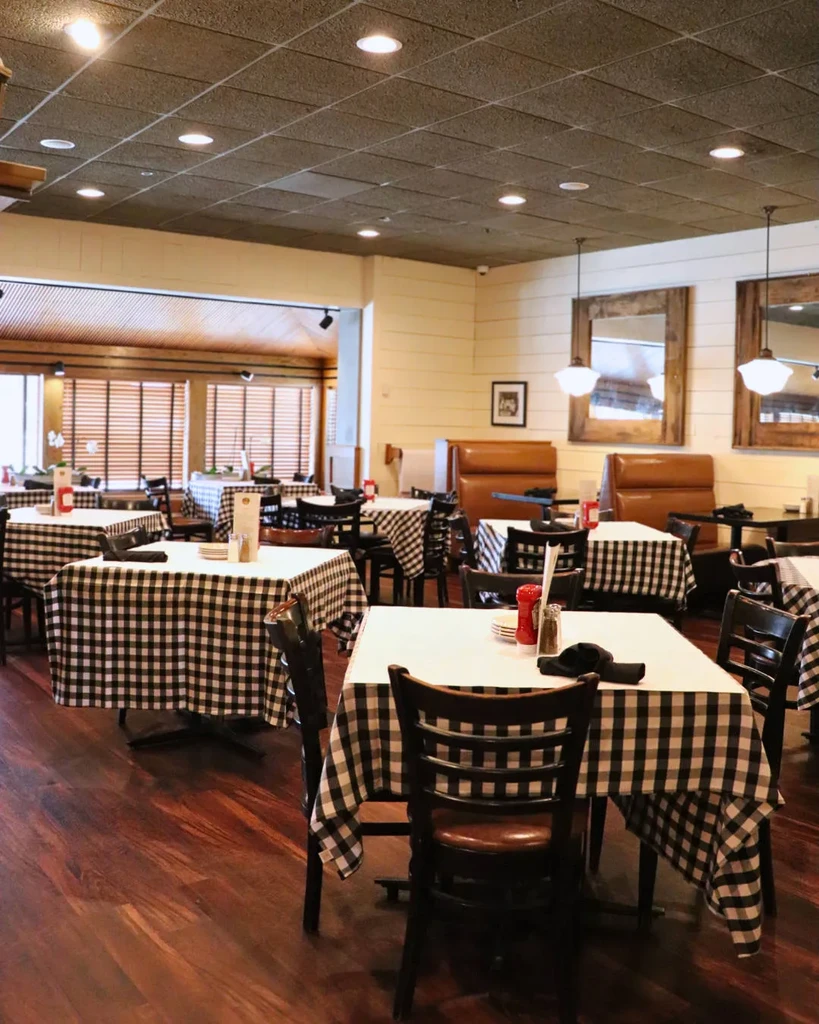 Empty restaurant interior with checkered tables, booths, and rustic mirrors.