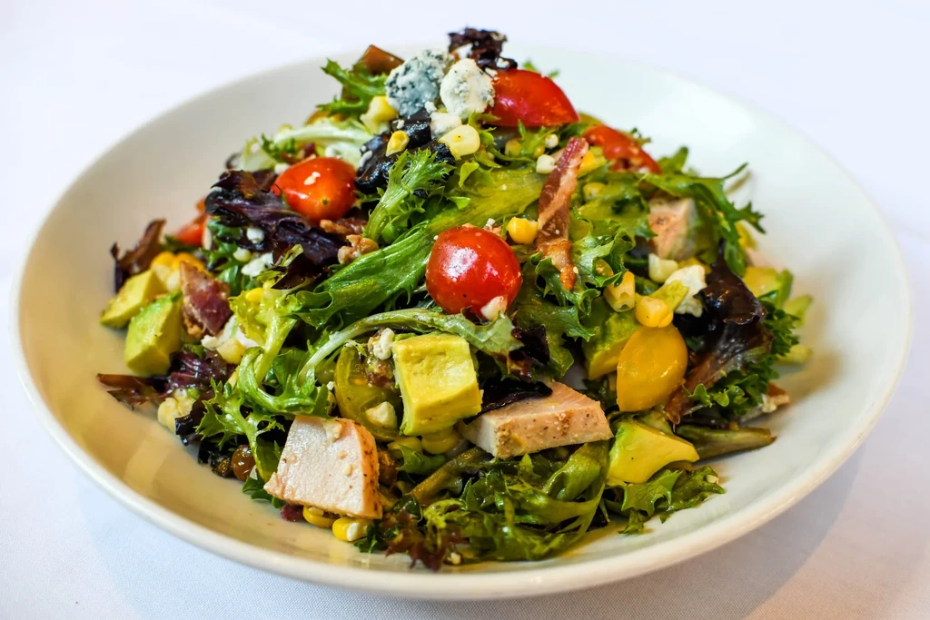 Vibrant salad with chicken, avocado, tomatoes, blue cheese, and bacon.