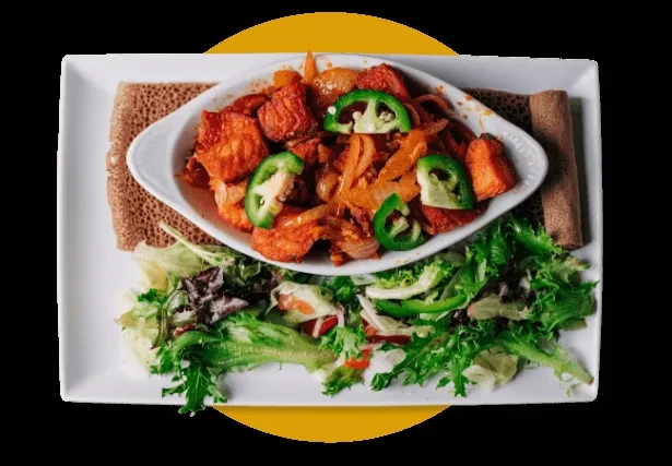 Overhead of vibrant stir-fry, salad, and injera on white plate.