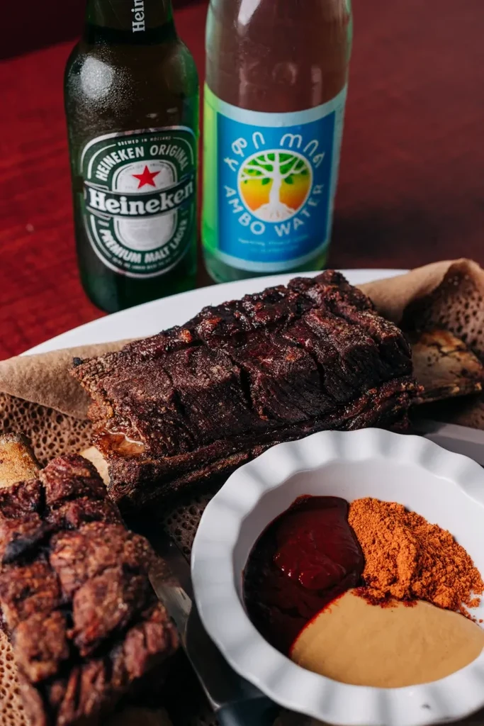 Ethiopian braised meat, injera, three condiments, Heineken, and Ambo water.