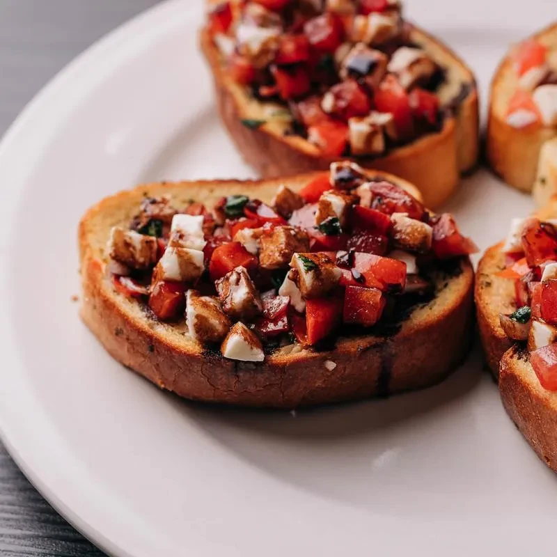 Toasted bruschetta with tomatoes, mozzarella, balsamic glaze, and green herbs.
