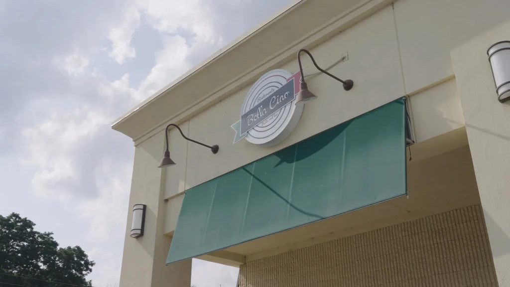 Circular 'Ristorante Bella Ciao - Crafts and Bar' sign on a cream building.