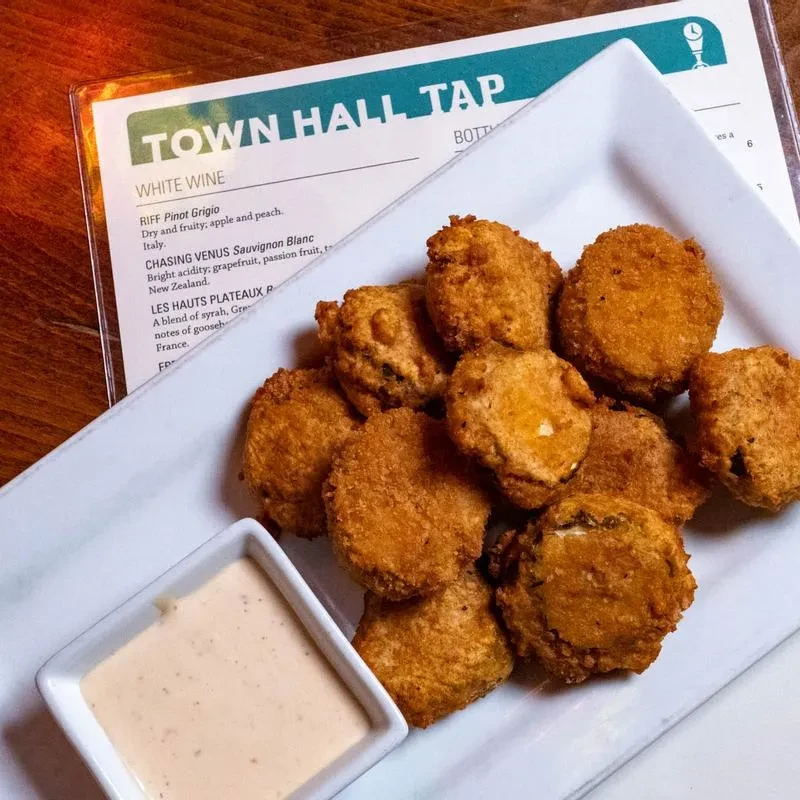 Golden-brown fried appetizers with creamy sauce on a white plate.