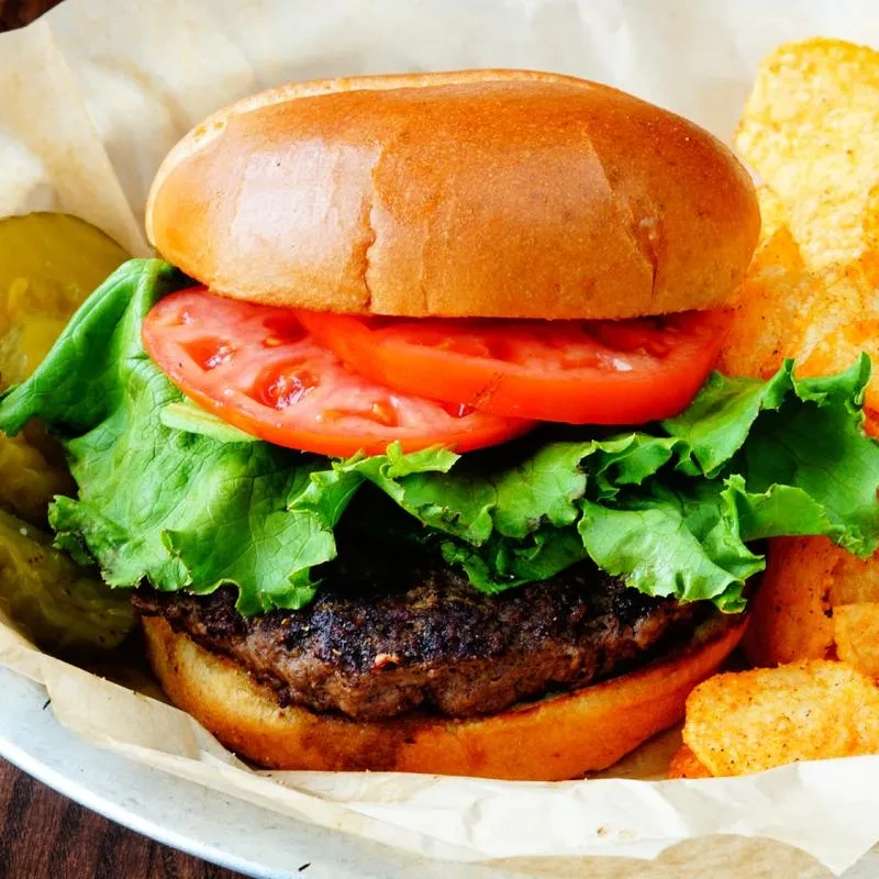 A classic hamburger with lettuce, tomato, pickles, and seasoned potato chips.