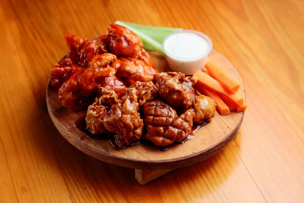 Platter of buffalo and dark-sauced chicken wings, celery, carrots, dip.