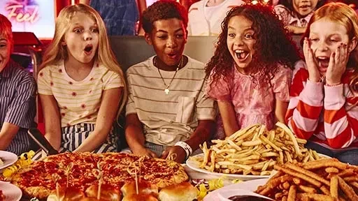Five children react with surprise and excitement to a large meal.