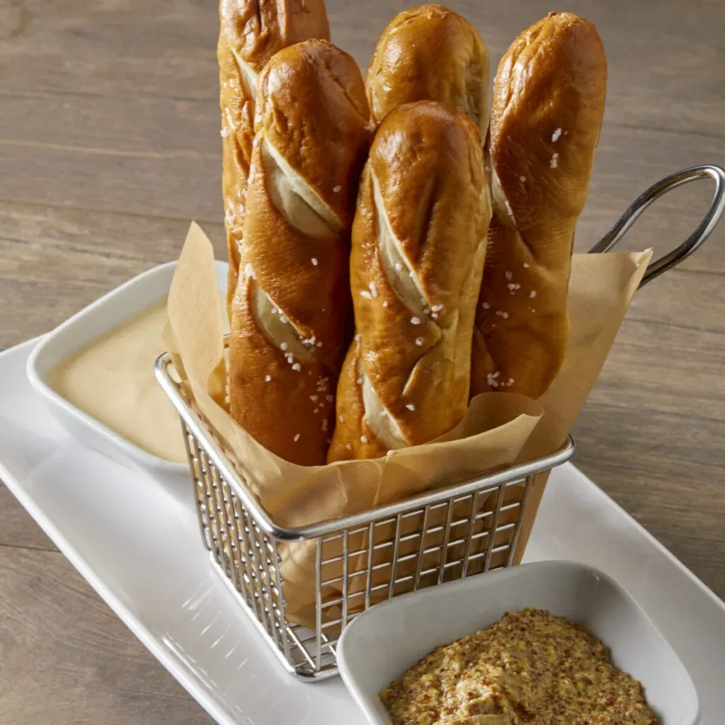 Soft, golden pretzel sticks with coarse salt, cheese sauce, and mustard.
