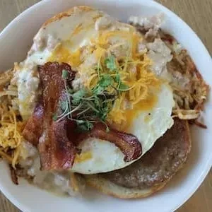 Biscuit, sausage, eggs, gravy, bacon, hash browns, and microgreens.