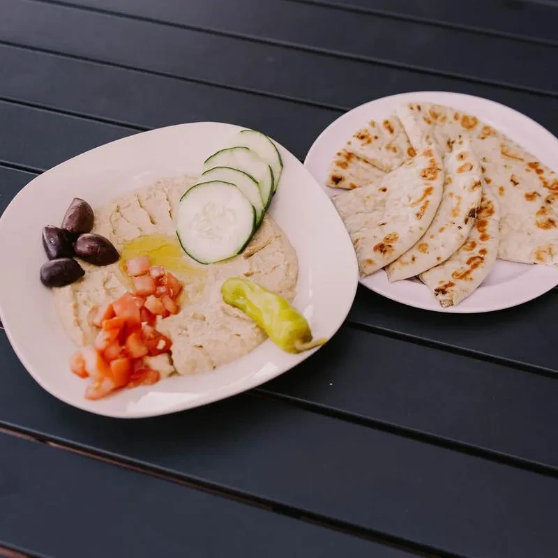 Hummus with tomatoes, olives, cucumber, pepperoncini, and toasted flatbread.