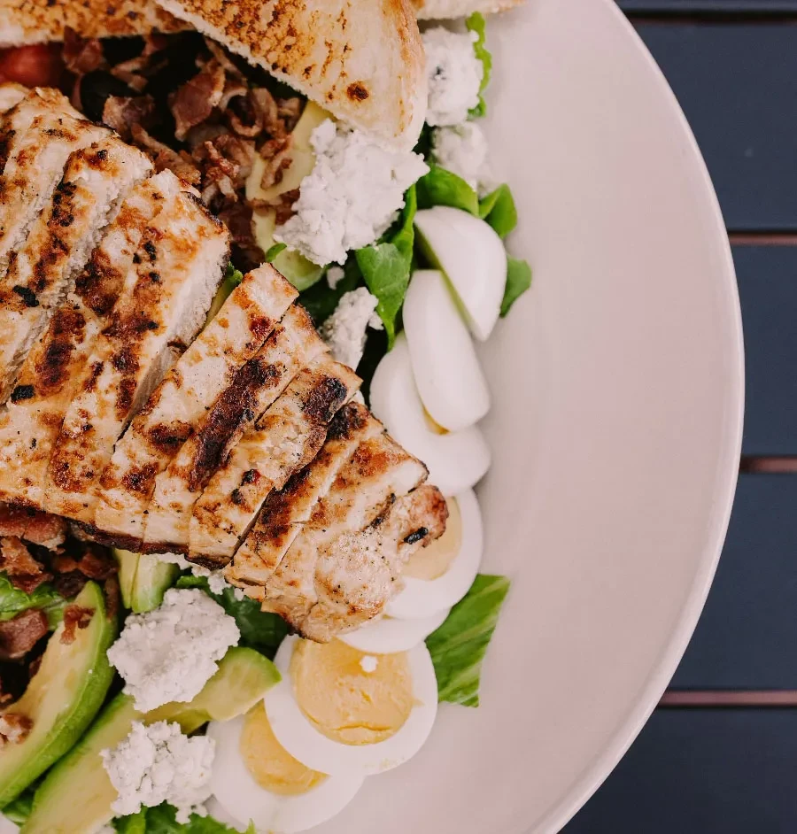 Top-down view of a Cobb salad with grilled chicken, avocado, eggs, bacon.