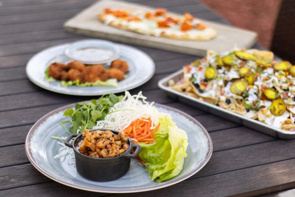 Table laden with lettuce wraps, fried food, and loaded nachos.