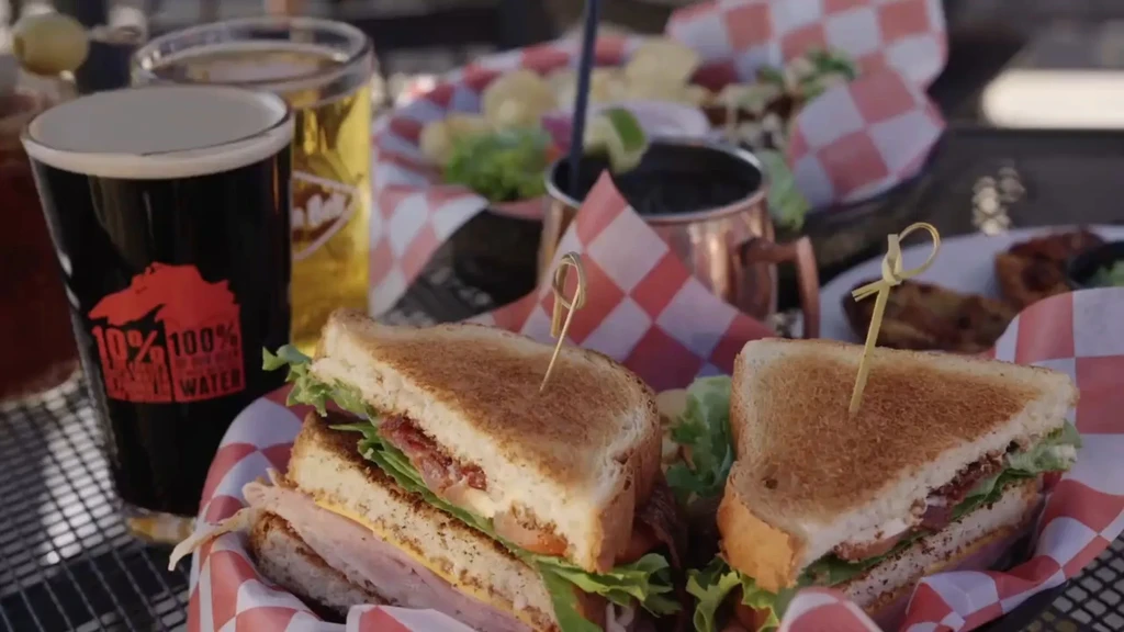 Close-up of club sandwich, dark and amber drinks on a table.