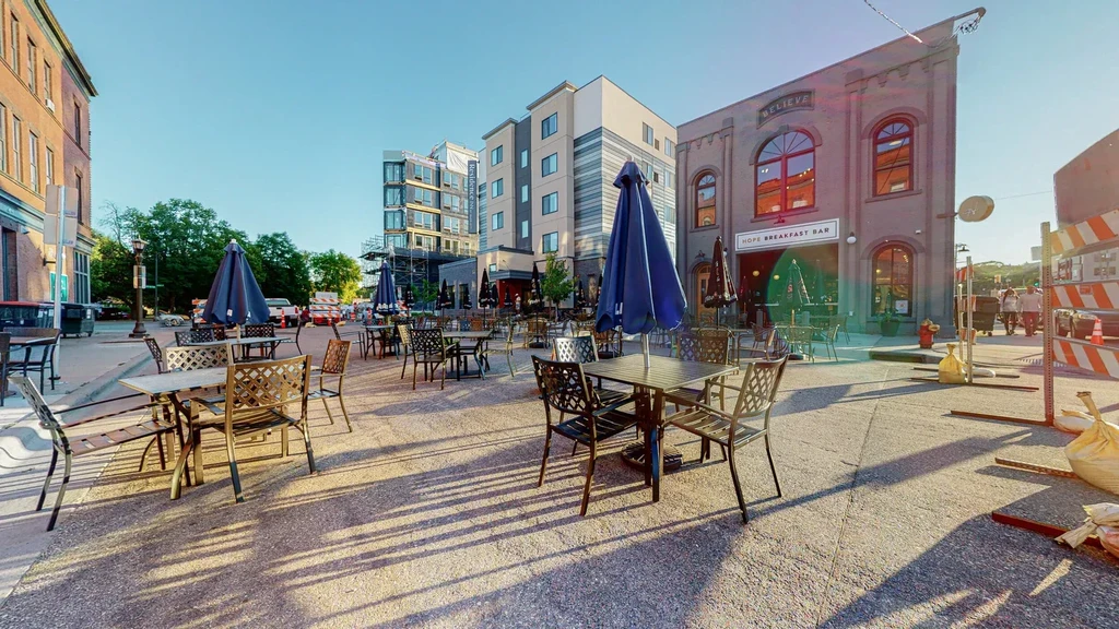 Hope Breakfast Bar's empty sunny outdoor patio with blue umbrellas.