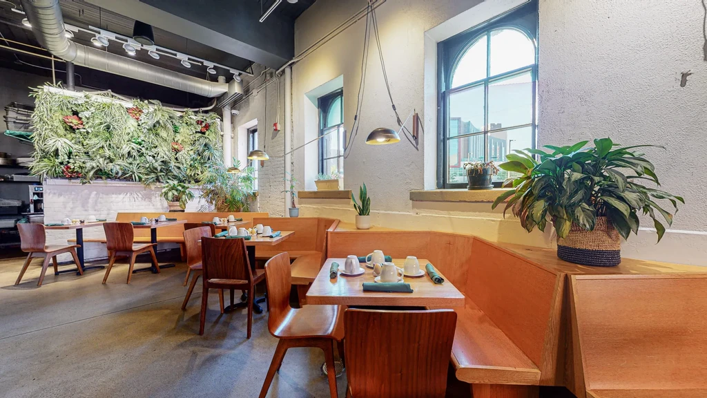 Modern restaurant with large living wall, industrial design, and wooden seating.