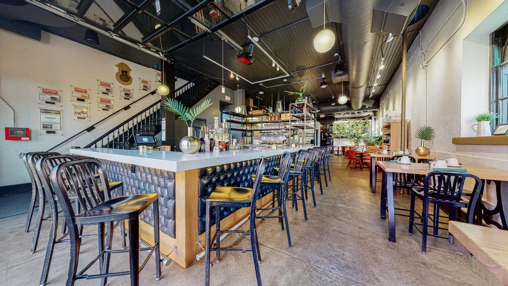 Empty modern bar and dining area with industrial ceiling and green wall.