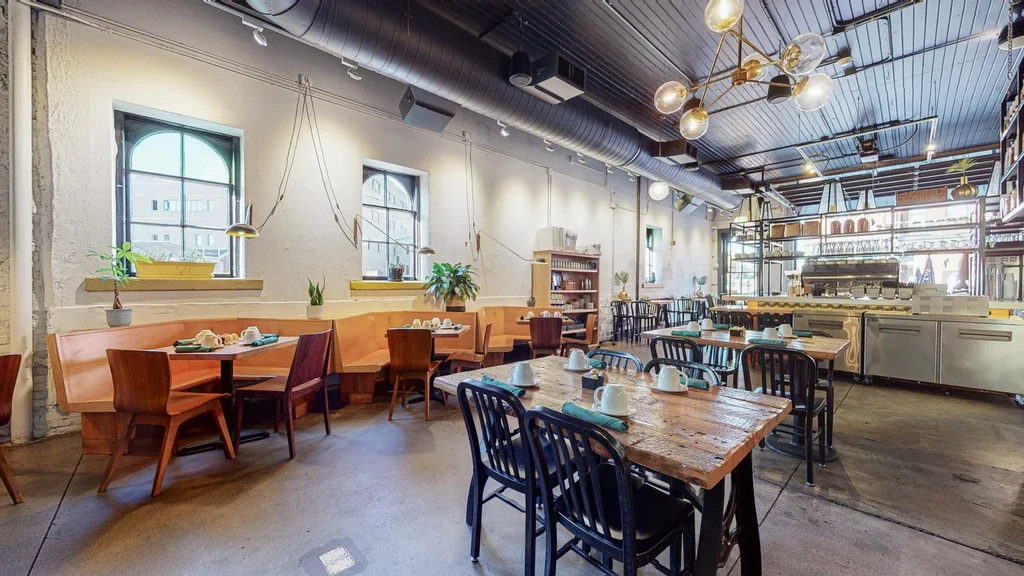 Empty modern restaurant interior, industrial-contemporary, featuring arched windows and a bar.