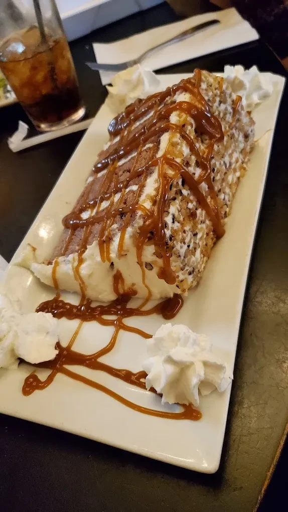 Dessert with whipped cream, caramel, and nuts on a white plate.