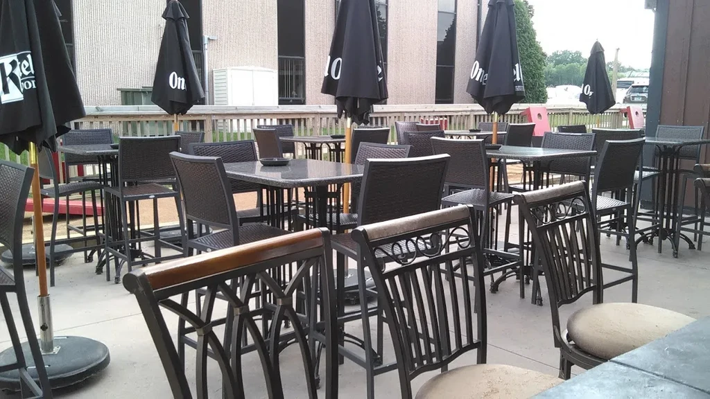 Empty casual outdoor patio with dark high-top tables and umbrellas.