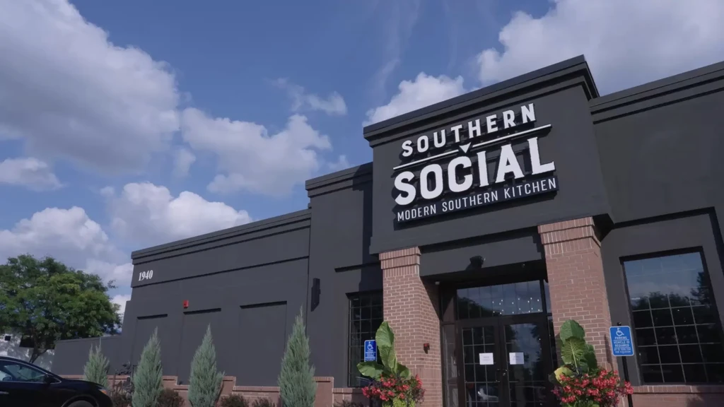 Modern dark grey Southern Social restaurant with brick accents and flowers.